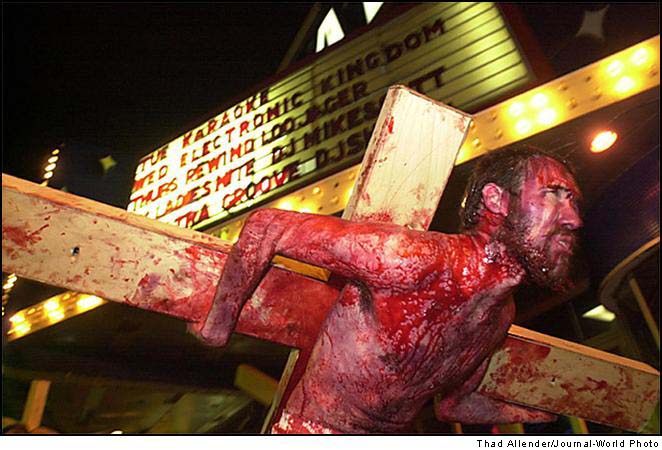 brutal depiction of blood-streaked man carrying cross